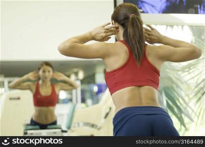 A woman works out at a gym looking at her reflection
