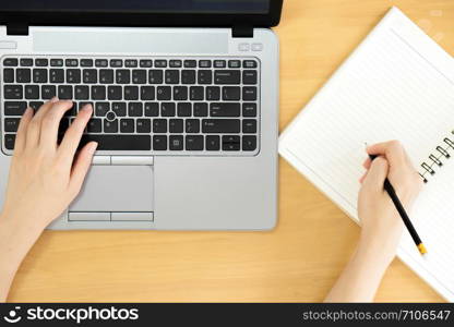 A women hands using laptop with blank screen and writing in notepad