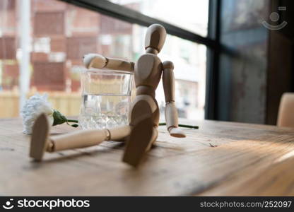 a wood man is sitting and put the arm on the glass of water