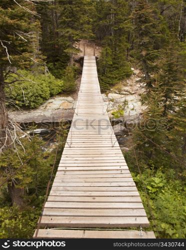 A wood suspension bridge provides a somewhat precarious crossing over a stream in Glacier National Park.
