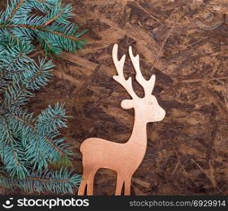 A wooden background with a green spruce branch and a wooden toy
