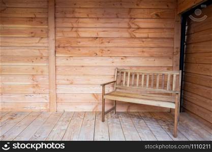 A wooden bench seat on a wooden porch, with wood roof close-up new interior modern close-up. A wooden bench seat on a wooden porch, with wood roof close-up new interior modern