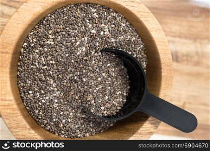 A wooden bowl on the table holds Chia Seeds with scoop