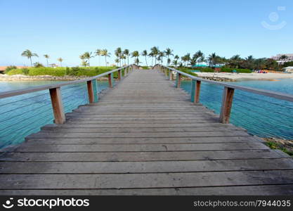 A wooden bridge over water going over to a beach