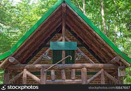 A wooden cabin with walking boots and walking stick in a forest