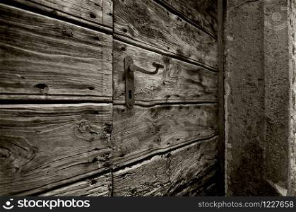 a wooden door with an iron handle on a stone frame