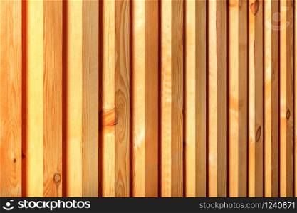 A wooden fence with a ribbed texture, a beautiful tree pattern in the form of smooth trunks with vertical guides.. Texture and background of a new natural wooden fence with vertical bars.