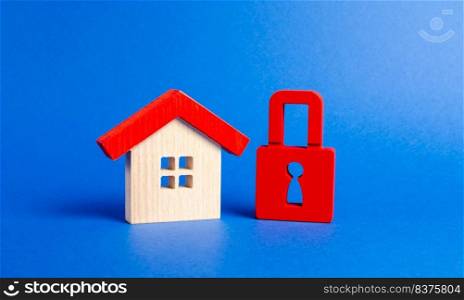 A wooden house and a red padlock. Unavailable and expensive real estate. house Insurance. Security and safety. Confiscation for debts. alarm system. seizure of property. Protection of property rights.