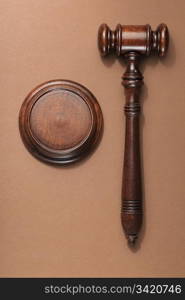 A wooden mahogany gavel with sound block on brown background.