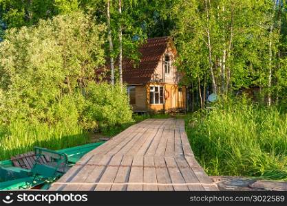 A wooden pier running from the lake to the fisherman&rsquo;s house on the shore of the pond