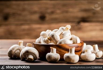 A wooden plate full of fresh mushrooms. On a wooden background. High quality photo. A wooden plate full of fresh mushrooms.