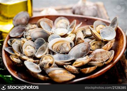 A wooden plate full of fresh vongole. Against a dark background. High quality photo. A wooden plate full of fresh vongole.