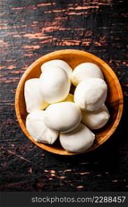 A wooden plate on a table with mozzarella. Against a dark background. High quality photo. A wooden plate on a table with mozzarella.