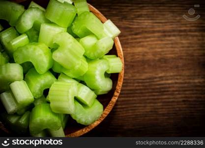 A wooden plate with a piece of celery. On a wooden background. High quality photo. A wooden plate with a piece of celery.