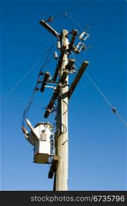 A wooden pole supporting a transformer and power lines