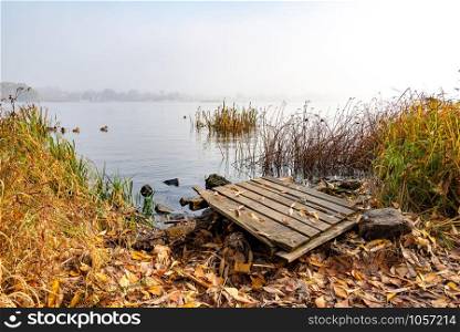 A wooden pontoon over big stones close to the blue Dnieper river is waiting for the fisherman.