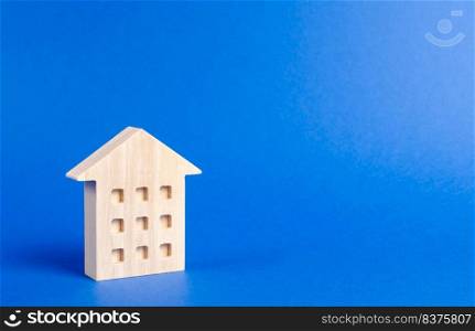 A wooden residential building stands on a blue background. The concept of buying and selling real estate, renting. Search for a house. Affordable housing, credit and loans. Investments. place for text