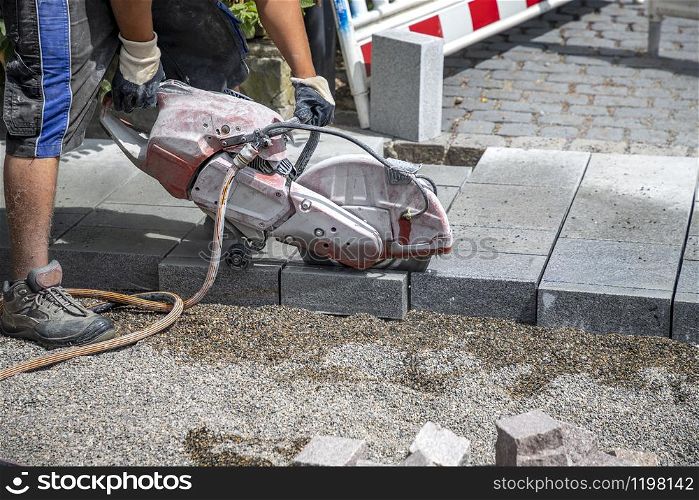 A worker cuts a tile to size with an electric grinder to complete the self-locking paving
