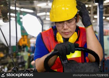 A worker with yellow safety helmet and goggles driving a forklift or reach truck having a strong headache or sick at the logistics warehouse store.