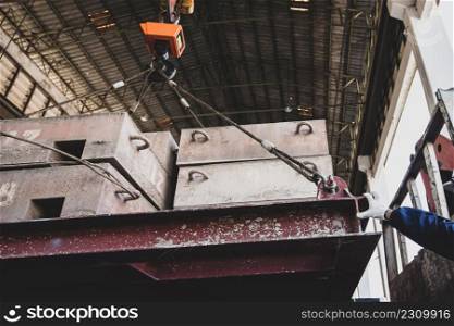 A workman?s hands in a glove controlling electric cable hoist, heavy hoist iron hook lifting of structure platform on the large steel box. Focus on a hand.