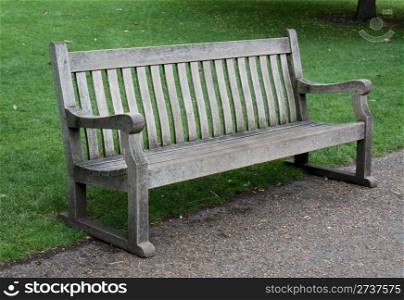 A worn wooden bench in a park.