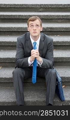 A worried business man sitting on some stairs