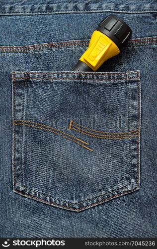 A yellow and black flash light in the back pocket of a denim jeans pants.