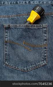 A yellow and black flash light in the back pocket of a denim jeans pants.