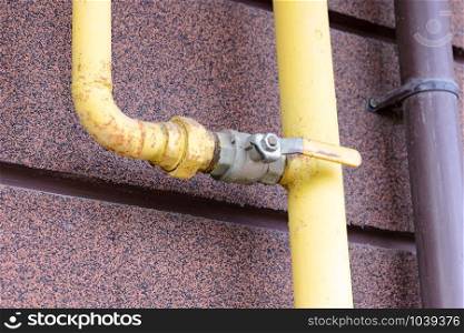 A yellow gas tube, with a tap, outside of a house to canalize the soft energy at home.