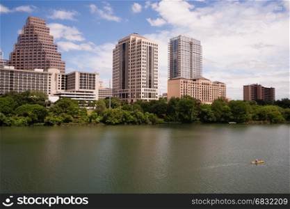 A yellow kayak floats along through Austin on the riverfront