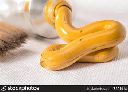 A Yellow Ochre oil paint paste is pressed from a tube on to a white canvas.