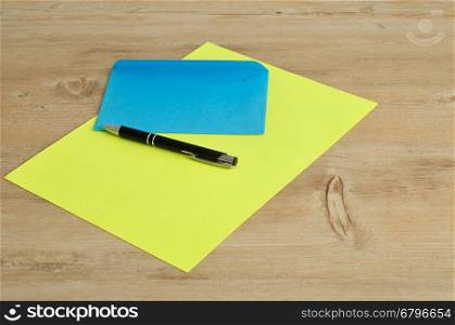 A yellow paper and a blue envelope with a black pen