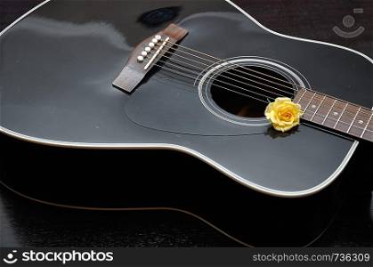 A yellow rose displayed with a guitar