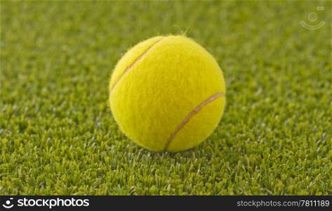 A yellow tennis ball over the green grass