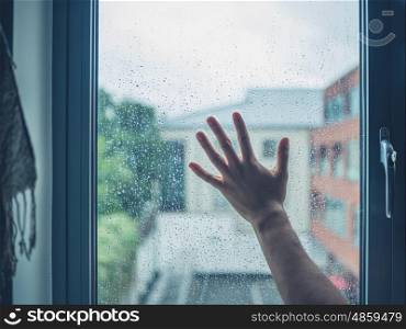A youg man's hand is wiping the dew from a window