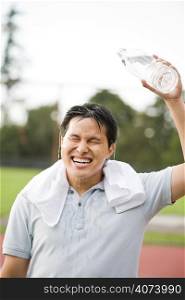 A young active sporty asian male cooling down by pouring water on top of his head after exercise