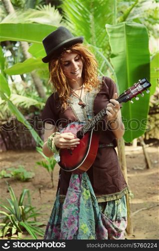 A young actress with mandalina playing against a tropical forest