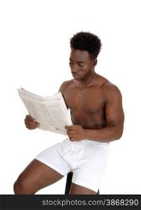 A young African American man sitting in white underwear on a chair,reading the paper, isolated for white background.