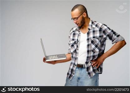 A young african american man working with a laptop pc.. A young african american man working with a laptop pc