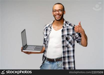 A young african american man working with a laptop pc.. A young african american man working with a laptop pc