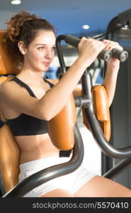 A young and beautiful woman working out at the gym at the end of the day with sunset light