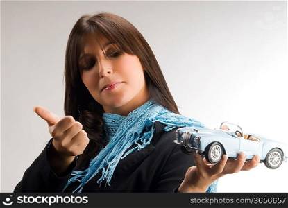 a young and elegant woman looking with interest at a model of a lancia car