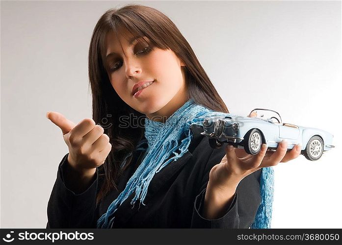 a young and elegant woman looking with interest at a model of a lancia car