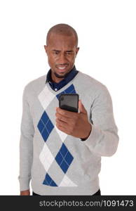 A young angry African American man standing in a sweater with his phone in his hand confused what hi sees, isolated for white background