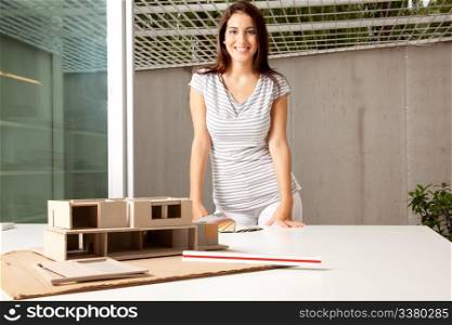 A young architect in an office with a rough model of a house