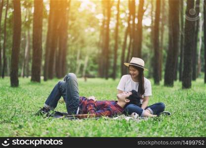A young asian lover couple sitting and lying down together in the park