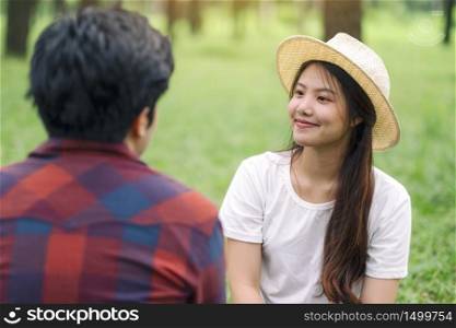 A young asian lover couple sitting together in the park