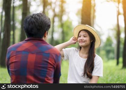 A young asian lover couple sitting together in the park
