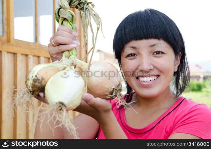 a young asian woman holds fresh onion and smiles