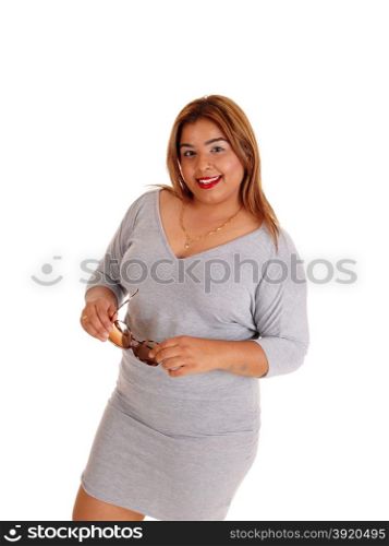 A young Asian woman in a tight gray dress holding her sunglasses,standing isolated for white background.
